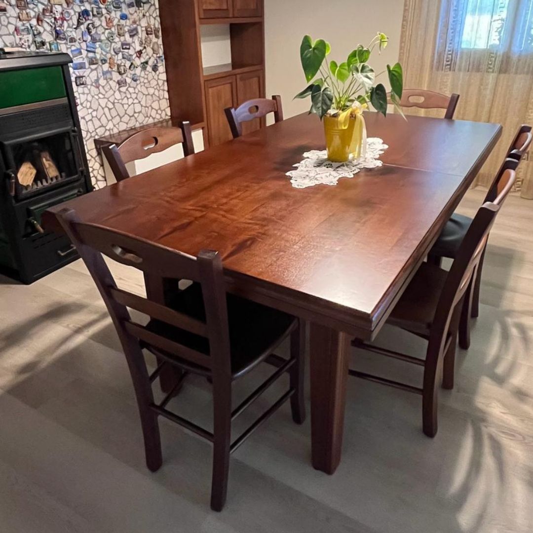 Tavolo fratino allungabile in legno noce scuro con centrotavola decorativo.